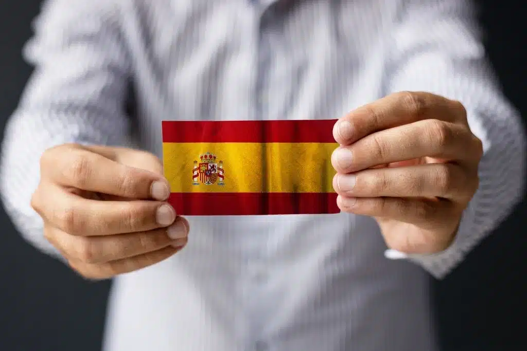 Arraigo de segunda oportunidad: manos sosteniendo la bandera de España para regularizar la residencia